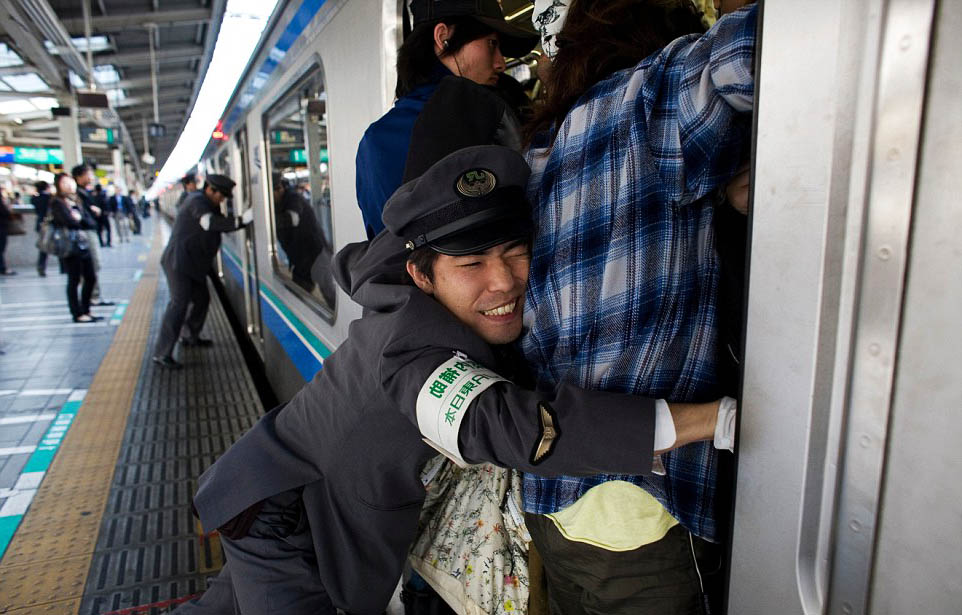 pegawai terpaksa menolak penumpang masuk ke dalam kereta api di jepun